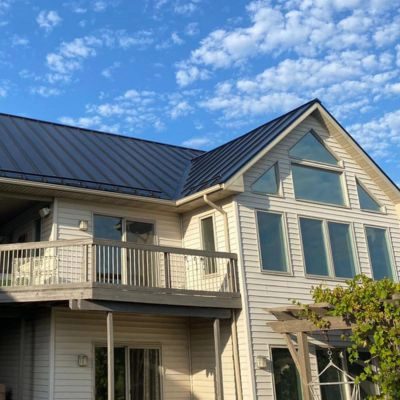 tan two story house with dark standing seam metal roof