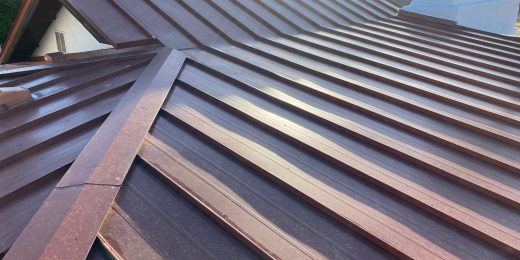 A brick red standing seam metal roof on a house.